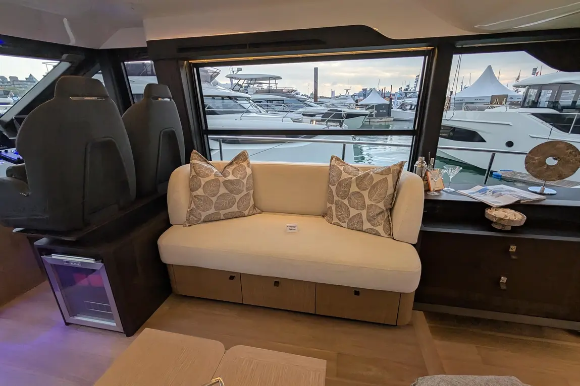 Modern yacht interior featuring a cosy sofa with leaf-patterned cushions, boat views, and luxury decor elements.